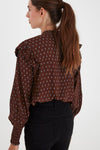 Back view of model wearing ICHI Carina long sleeve printed blouse. Cappuccino brown with light blue print. Frilled detail at shoulders, shirred cuffs. 